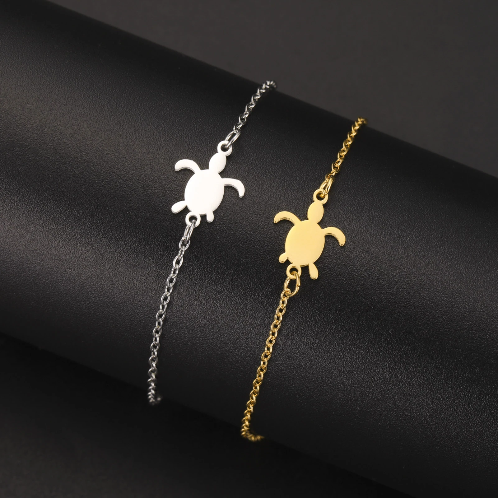 Deux bracelets fins avec silhouette de tortue, en finitions claire et dorée