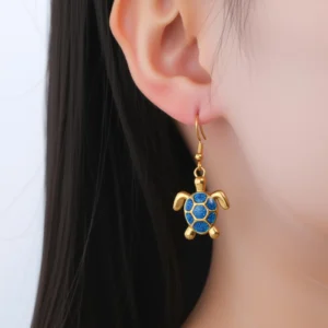 Boucle d’oreille pendante en forme de tortue bleue portée à l’oreille