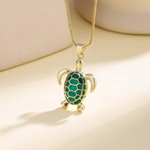 Collier à pendentif tortue vert et doré présenté sur un buste clair