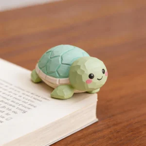 Petite tortue décorative verte posée sur les pages d’un livre